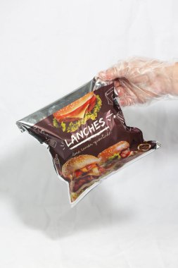 Hamburger teslimatı için termal paket tek kullanımlık eldivenle tutuluyor. Paket yemek, fast food, hijyen, gıda güvenliği ve modern dağıtım hizmeti kavramı.