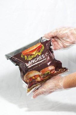 Hamburger teslimatı için termal paket tek kullanımlık eldivenle tutuluyor. Paket yemek, fast food, hijyen, gıda güvenliği ve modern dağıtım hizmeti kavramı.