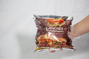 Hamburger teslimatı için termal paket tek kullanımlık eldivenle tutuluyor. Paket yemek, fast food, hijyen, gıda güvenliği ve modern dağıtım hizmeti kavramı.