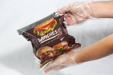 Hamburger teslimatı için termal paket tek kullanımlık eldivenle tutuluyor. Paket yemek, fast food, hijyen, gıda güvenliği ve modern dağıtım hizmeti kavramı.