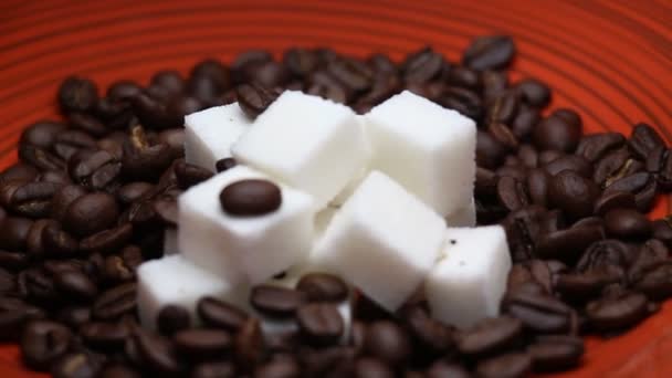 Grãos de café e cubos de açúcar girando em uma placa vermelha — Vídeo de Stock