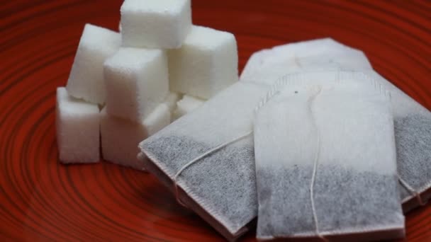 Cubes de sucre et sachets de thé tournant sur une plaque rouge — Video