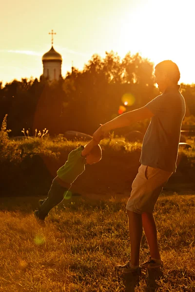 Feliz papá jugando con su hijo en el parque en un fondo de la iglesia . —  Fotos de Stock