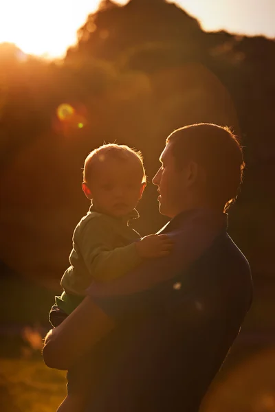 Feliz joven padre y su hijo en el sol al atardecer en el parque . —  Fotos de Stock