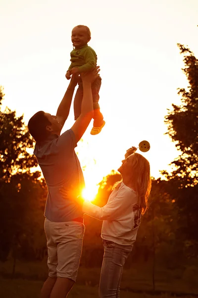 Padres jóvenes felices con su pequeño hijo oliendo, divirtiéndose y relajándose juntos en el parque . —  Fotos de Stock