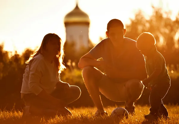 Shot de la familia de la religión feliz en el parque jugando con el pequeño hijo del treir en fútbol . —  Fotos de Stock