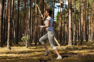Ormandaki aşırı açık fitness eğitimi sırasında oturum açmasına izin çalıştıran ve üstünden atlayarak genç fitness kadın.