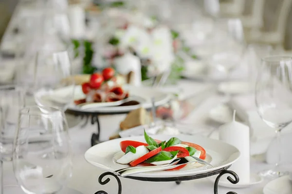 Restoran tablo beyaz tabaklar. Mozzarella peyniri, domates ve fesleğen bir plaka-kapreze veya caprese restarant içinde.