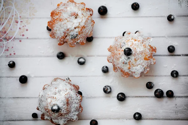 Pudra şekeri ve siyah kuş üzümü ya da beyaz tahtalar arka plan üzerinde yaban mersini Blueberry muffins.