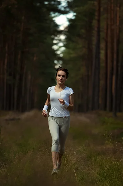 Działa kobieta biegania w terenie zalesionym lasu. — Zdjęcie stockowe