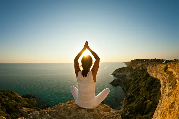 Красива підходить дівчина йога робить вправи йоги на вершині гори на заході сонця або сході сонця . — стокове фото