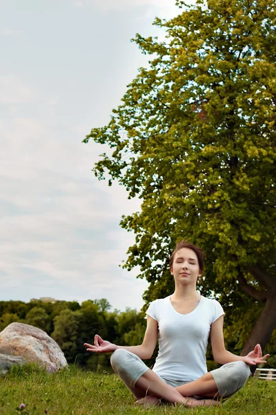 Meditating yoga woman in park on grass. Royalty Free Stock Photos