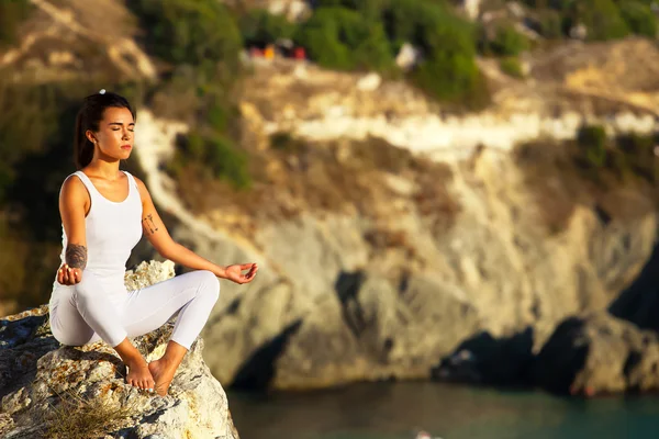 Mujer yoga meditando al atardecer o al amanecer en el mar negro Crimea . Imagen de stock