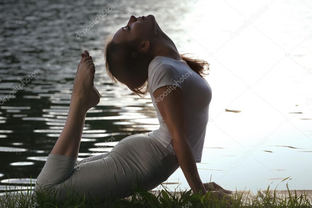 Woman meditating practicing yoga in park.