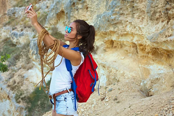 Schönes junges Bergsteiger-Mädchen macht ein Bild von sich selbst in den Bergen. Stockbild