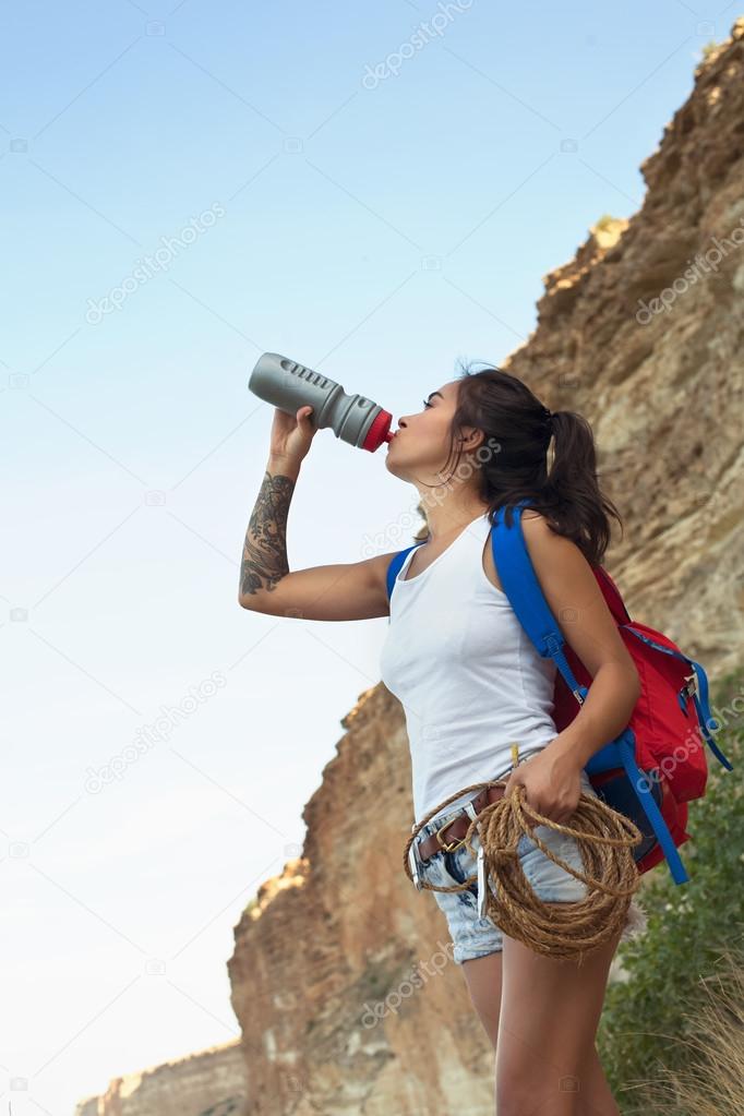 Beautiful multiculture girl drinking water in the mountains of Canyon New Crimea.
