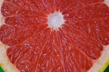 Olgun ve lezzetli meyveler, yarıya kesilmiş taze greyfurt, yeşil kumaş arka planında dilimlenmiş greyfurt..