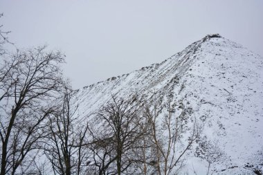 Aralığın sonunda ağaçlar ve çalılarla kaplı, beyaz pofuduk karla kaplı, yıpranmış bir yol boyunca büyük, yüksek bir dağ..
