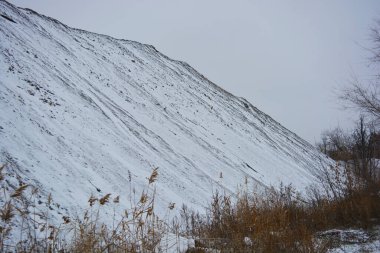 Aralığın sonunda ağaçlar ve çalılarla kaplı, beyaz pofuduk karla kaplı, yıpranmış bir yol boyunca büyük, yüksek bir dağ..