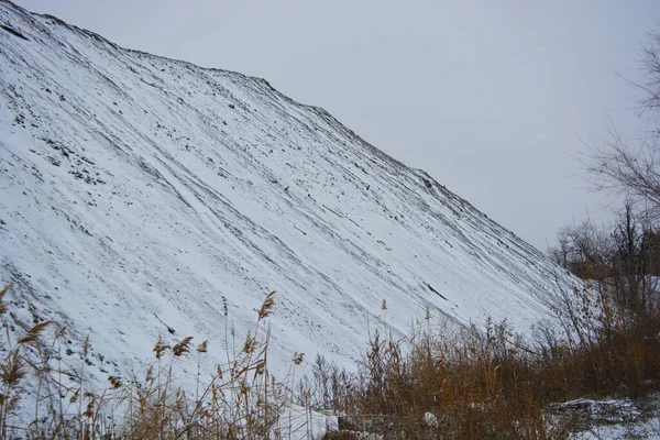 Aralığın sonunda ağaçlar ve çalılarla kaplı, beyaz pofuduk karla kaplı, yıpranmış bir yol boyunca büyük, yüksek bir dağ..