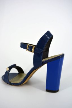 Bir şey daha, beyaz arka planda altın tabanlı geniş topuklu bir çift mavi lacquer sandalet..
