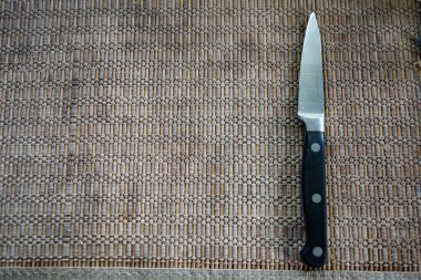 Metal küçük mutfak bıçağı, iplik ve bambu çubuklarından yapılmış alışılmadık eski bir peçetenin üzerinde bulunur.. 