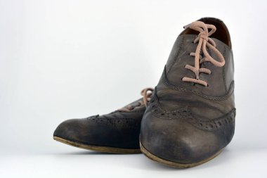 Beyaz arka planda dişi deri ayakkabılar var. Düz topuklu gri ayakkabı bağcıkları olan Oxford ayakkabıları. Gri kadın ayakkabıları, farkında olmadan bağlanıyor..