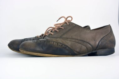 Beyaz arka planda dişi deri ayakkabılar var. Düz topuklu gri ayakkabı bağcıkları olan Oxford ayakkabıları. Gri kadın ayakkabıları, farkında olmadan bağlanıyor..