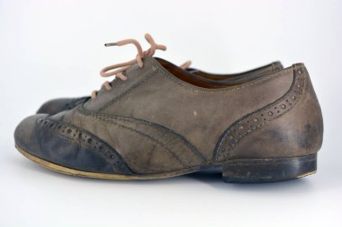 Beyaz arka planda dişi deri ayakkabılar var. Düz topuklu gri ayakkabı bağcıkları olan Oxford ayakkabıları. Gri kadın ayakkabıları, farkında olmadan bağlanıyor..