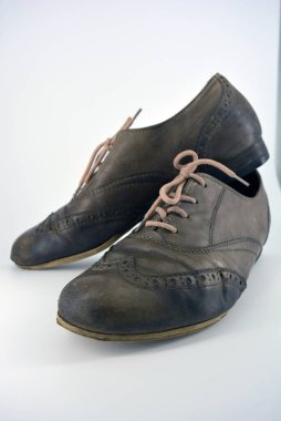 Beyaz arka planda dişi deri ayakkabılar var. Düz topuklu gri ayakkabı bağcıkları olan Oxford ayakkabıları. Gri kadın ayakkabıları, farkında olmadan bağlanıyor..