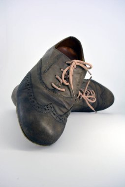 Beyaz arka planda dişi deri ayakkabılar var. Düz topuklu gri ayakkabı bağcıkları olan Oxford ayakkabıları. Gri kadın ayakkabıları, farkında olmadan bağlanıyor..