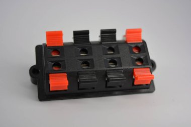 Beyaz plastik arka planda bulunan çıplak kabloların eş zamanlı bağlantısı için kırmızı ve siyah kıskaçlı kabloları tamir etmek için siyah elektrikli plastik kutu. 