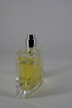 Güzel ve alışılmadık bir kadın parfümü şişesi. Beyaz arka planda sarı bir sıvı var.. 