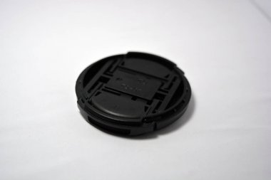 Siyah plastik bir lens kapağı beyaz bir arkaplana yerleştirilmiştir. 