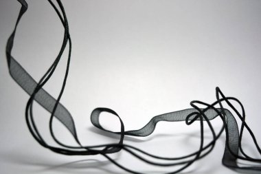 Beyaz yüzey boyunca rastgele yerleştirilmiş şeffaf kurdeleler ve kurdeleler. Narin siyahlar şeffaf sentetik kumaştan yapılır.. 