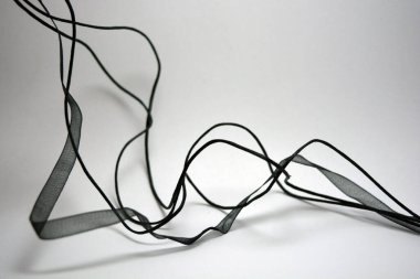 Beyaz yüzey boyunca rastgele yerleştirilmiş şeffaf kurdeleler ve kurdeleler. Narin siyahlar şeffaf sentetik kumaştan yapılır.. 