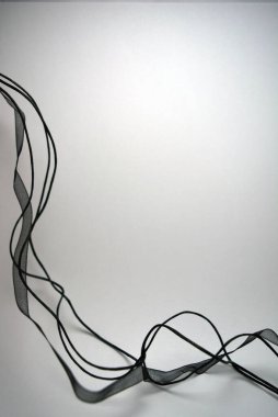 Beyaz yüzey boyunca rastgele yerleştirilmiş şeffaf kurdeleler ve kurdeleler. Narin siyahlar şeffaf sentetik kumaştan yapılır.. 