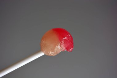 Lezzetli yuvarlak şeker, beyaz plastik çubukta beyaz pembe lolipop, beyaz plastik arka planda popüler şekerler..