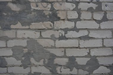 Construction renovation work, old wall with problems, flaws. Many large cracks in white brick wall, problem areas filled with cement that had fallen off. Poor, substandard construction work.