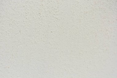 Construction and renovation work, plastering load-bearing street walls in sunlight. The white walls are coated with rough street primer with long micro-cracks throughout the surface and background.