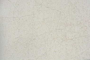 Construction and renovation work, plastering load-bearing street walls in sunlight. The white walls are coated with rough street primer with long micro-cracks throughout the surface and background.