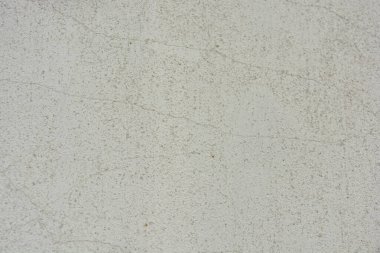 Construction and renovation work, plastering load-bearing street walls in sunlight. The white walls are coated with rough street primer with long micro-cracks throughout the surface and background.