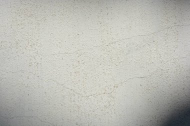 Construction and renovation work, plastering load-bearing street walls in sunlight. The white walls are coated with rough street primer with long micro-cracks throughout the surface and background.