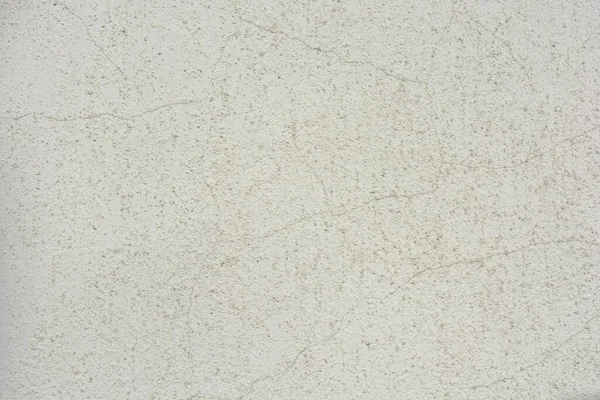 Construction and renovation work, plastering load-bearing street walls in sunlight. The white walls are coated with rough street primer with long micro-cracks throughout the surface and background.