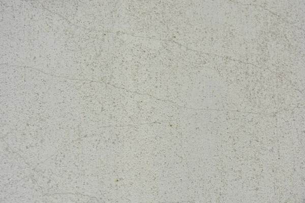 Construction and renovation work, plastering load-bearing street walls in sunlight. The white walls are coated with rough street primer with long micro-cracks throughout the surface and background.