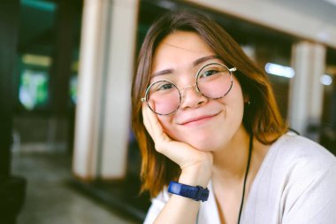 Genç Asyalı kadının yakın plan fotoğrafı. Geçmişi bulanık gözlük takıyor..