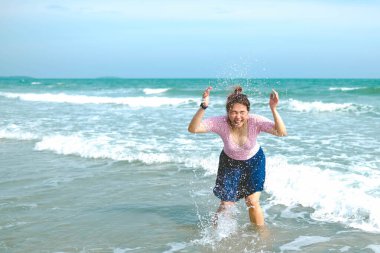 Mayolu genç Asyalı kadın sahilde su oynuyor..