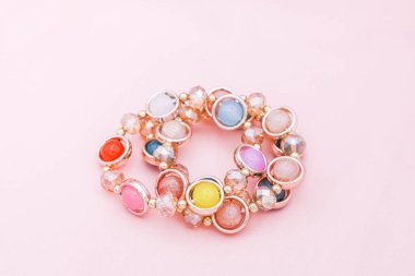 Pembe arka planda renkli boncuk bilezikler..