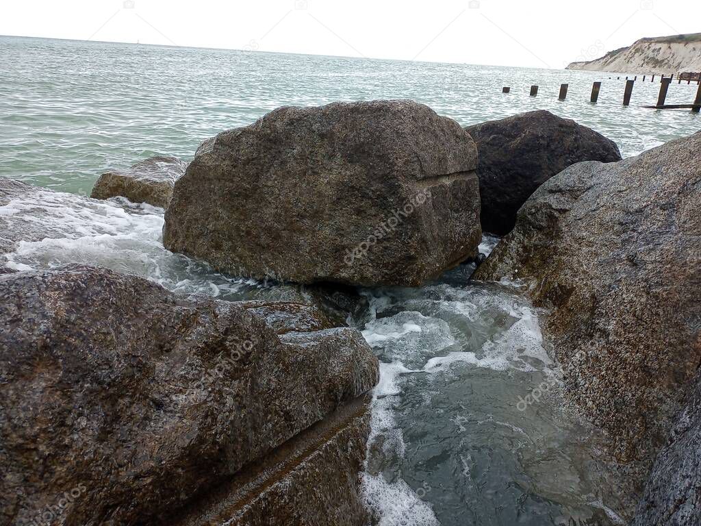 beach side ocean waves on rocks beachfront by pier grey black white splash water seaside