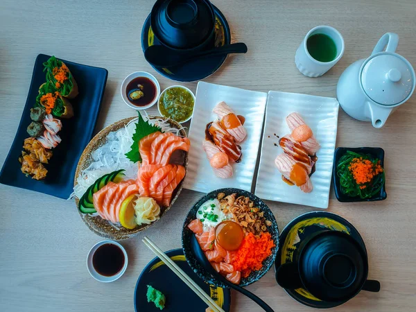 Japon yemeği saşimi somonu ve farklı türde suşi ve deniz yosunu salatası ve gari (zencefil) Japon restoranındaki servis panosunun sağ üst kısmında sağlıklı bir yemektir.